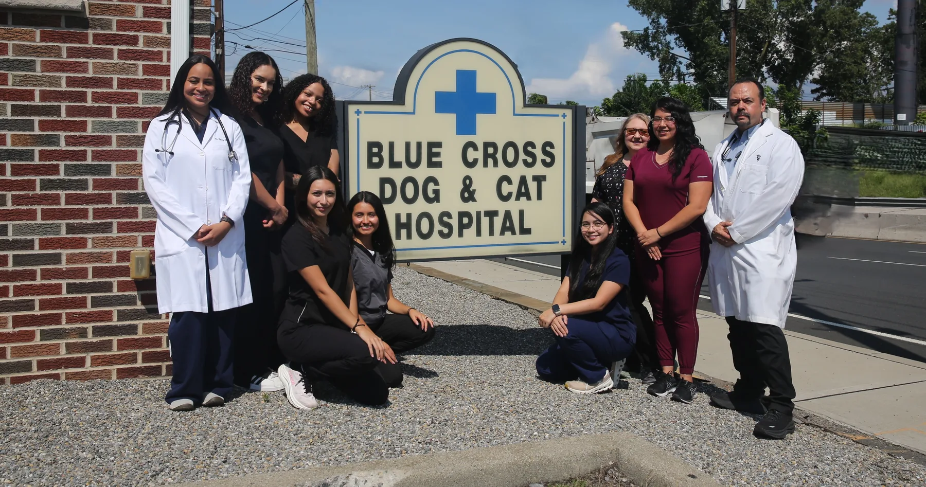 The Blue Cross Dog and Cat Hospital team with Dr. Sova and Dr. Caba at the hospital sign on McLean Blvd in Paterson